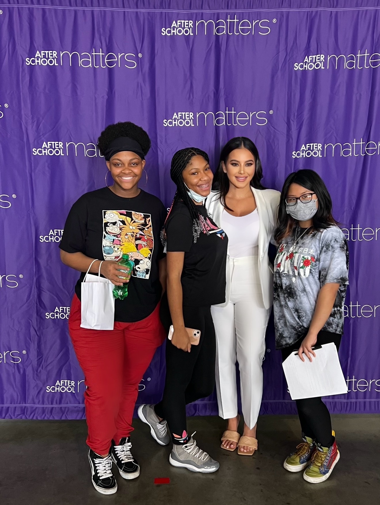 Talia Ramos with After School Matters youth participants in front of purple branded backdrop
